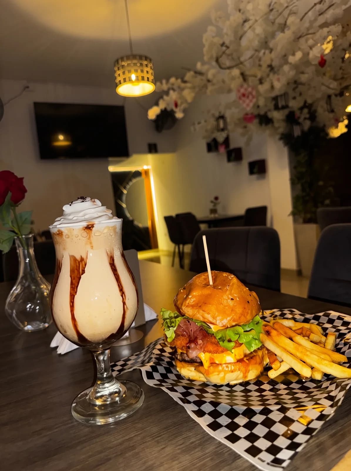 Hamburguesa con papas y malteada en una mesa de La Mesa de Oro, de noche